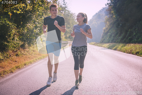 Image of young couple jogging along a country road