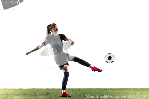 Image of Female soccer player kicking ball isolated over white background