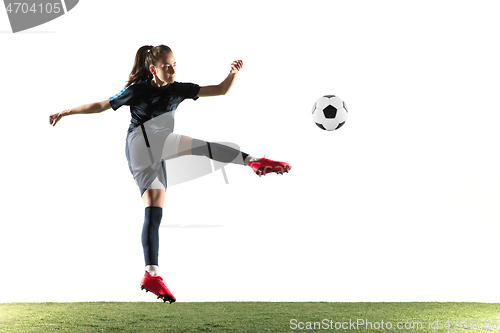 Image of Female soccer player kicking ball isolated over white background