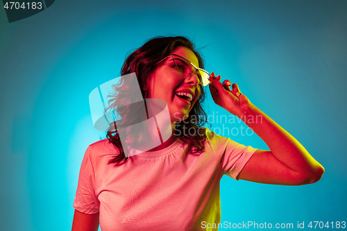 Image of Happy young woman standing and smiling against blue background