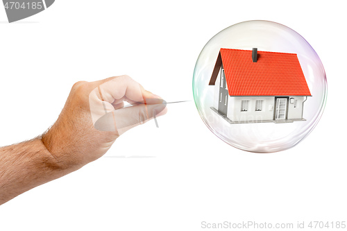 Image of soap bubble with a house and a males hand with needle to let the
