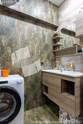 Image of Bathroom interior with beautiful tiles, a view of the washbasin built into the furniture with a mirror and a washing machine