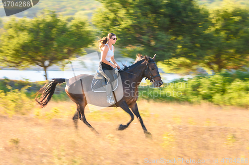 Image of Girl rides a horse across the field