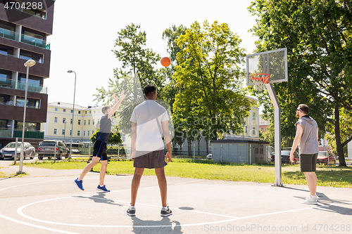 Image of group of male friends playing street basketball