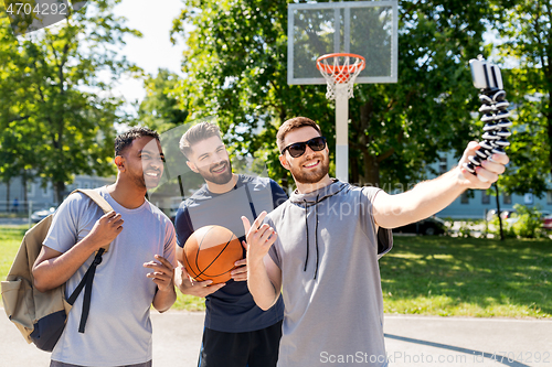 Image of happy men taking selfie at basketball playground