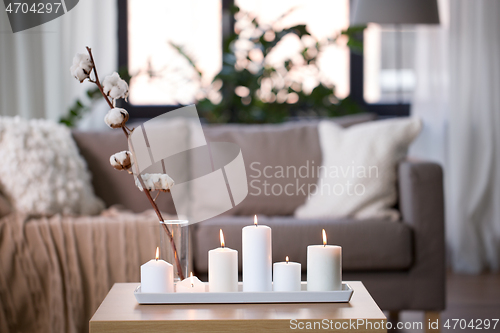 Image of burning white candles on table at cozy home