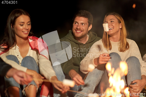 Image of friends roasting marshmallow on camp fire at night