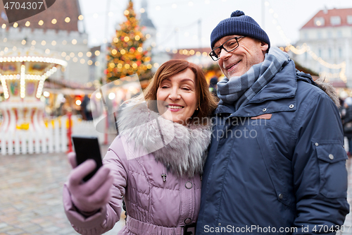 Image of senior couple taking selfie at christmas market