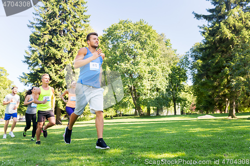 Image of happy young sportsmen racing wit badge numbers