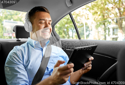 Image of passenger with headphones using tablet pc in car