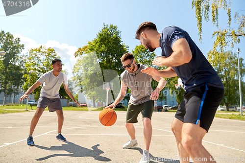 Image of group of male friends playing street basketball