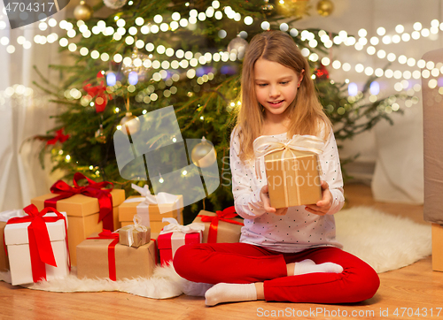 Image of smiling girl with christmas gift at home
