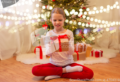 Image of smiling girl with christmas gift at home