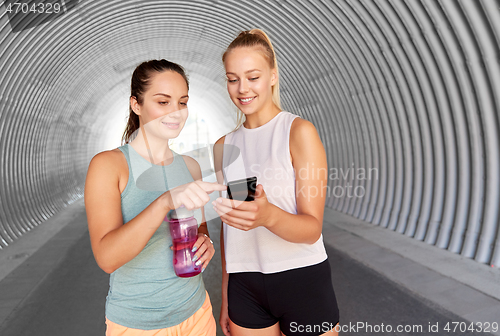 Image of women or female friends with smartphone and flask