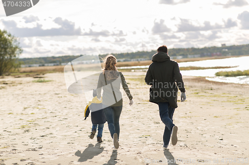 Image of happy family running along autumn beach