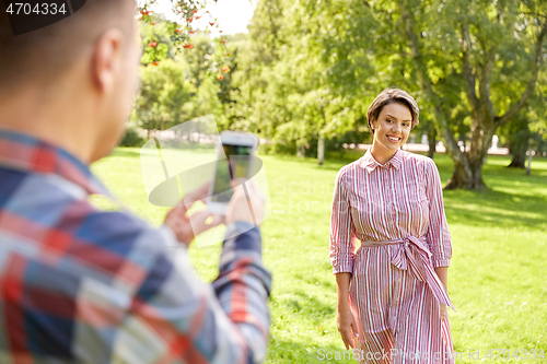 Image of couple photographing by smartphone in park