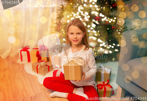 Image of smiling girl with christmas gift at home