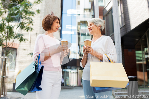 Image of senior women with shopping bags and coffee in city