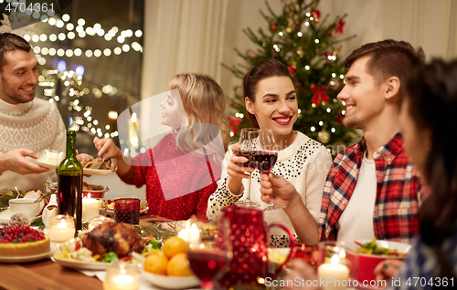 Image of happy friends having christmas dinner at home