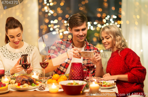 Image of happy friends having christmas dinner at home