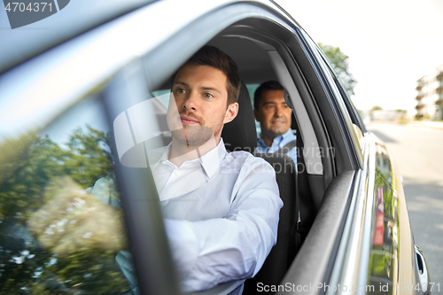 Image of male driver driving car with passenger