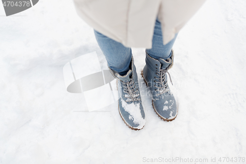 Image of female feet in winter shoes on snow from top