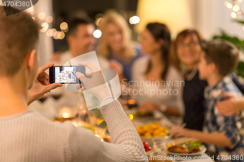 Image of man taking picture of family at dinner party