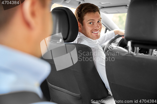 Image of male driver driving car and looking at passenger