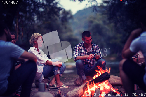 Image of young friends relaxing around campfire