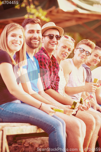 Image of friends enjoying watermelon while sitting on the wooden bridge