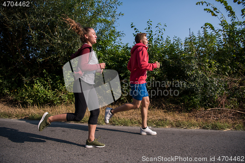 Image of young couple jogging along a country road