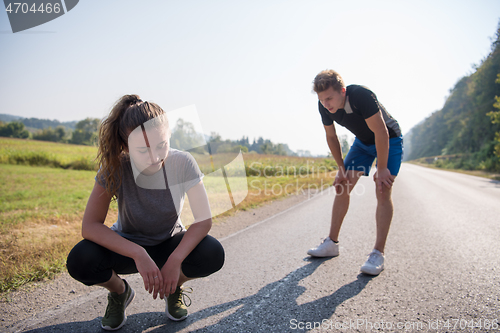 Image of young couple warming up and stretching on a country road