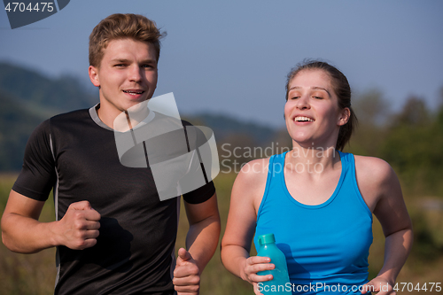 Image of young couple jogging along a country road