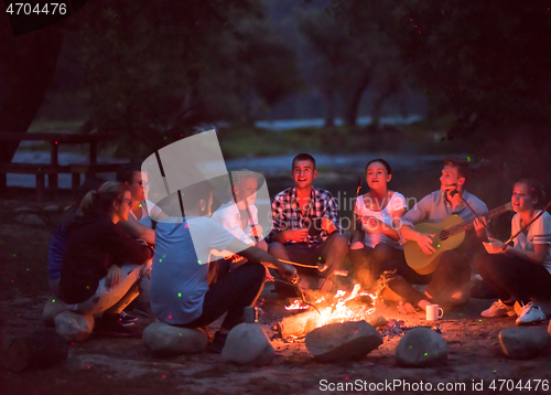 Image of young friends relaxing around campfire