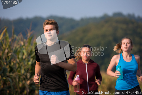 Image of young people jogging on country road