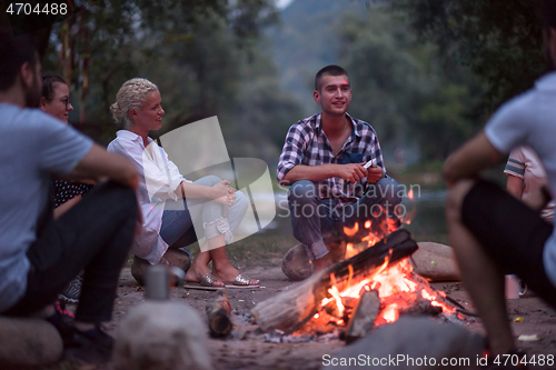 Image of young friends relaxing around campfire