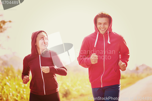 Image of young couple jogging along a country road