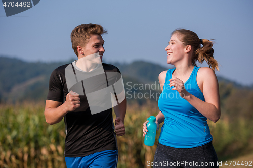 Image of young couple jogging along a country road