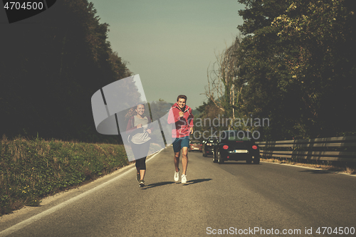 Image of young couple jogging along a country road