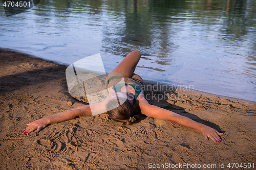 Image of girl in a green bikini relaxing on the riverbank