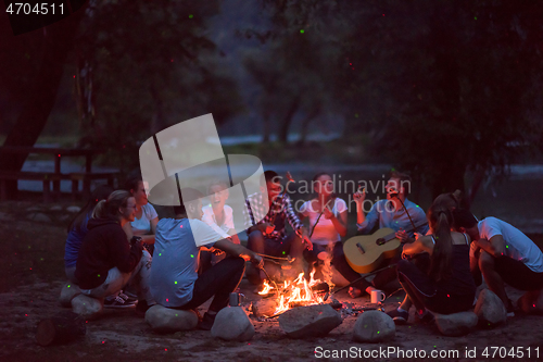 Image of young friends relaxing around campfire