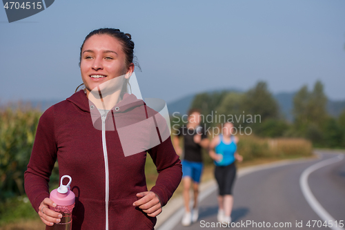 Image of young people jogging on country road