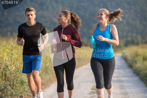 Image of young people jogging on country road