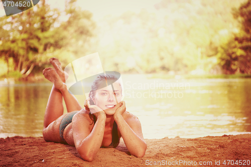 Image of girl in a green bikini relaxing on the riverbank