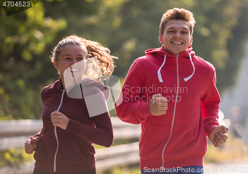 Image of young couple jogging along a country road