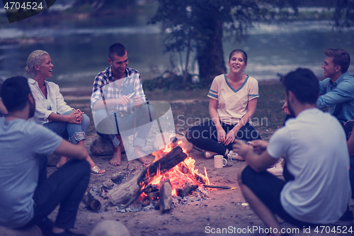 Image of young friends relaxing around campfire