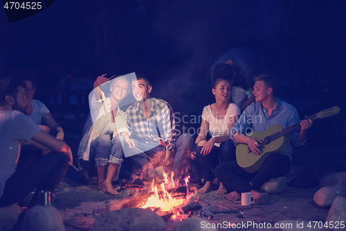 Image of young friends relaxing around campfire