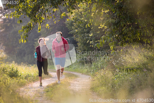 Image of young couple jogging along a country road