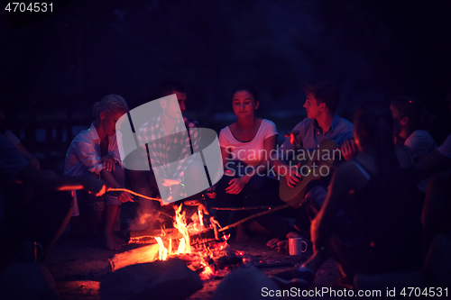 Image of young friends relaxing around campfire