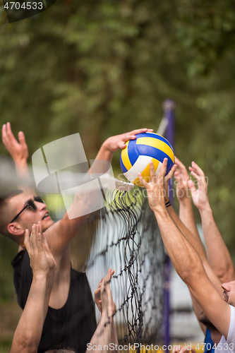 Image of group of young friends playing Beach volleyball